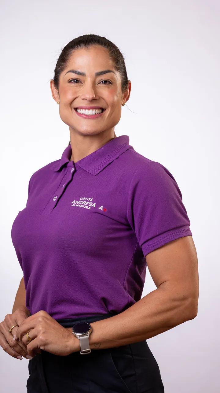 Capitã Bombeira Andresa em retrato de estúdio, sorrindo, de polo roxa da campanha.